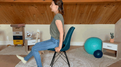 Une praticienne assise sur une chaise tend une jambe devant elle pendant un exercice.