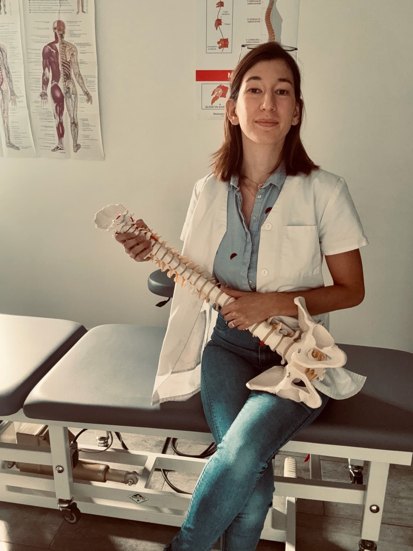 Eva Tang présente un modèle anatomique de la colonne vertébrale dans son espace de travail.